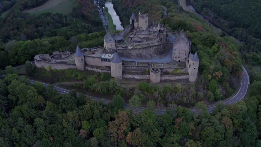 Aerial view of medieval castle surrounded by autumn trees and hills, Bourscheid, Luxembourg.