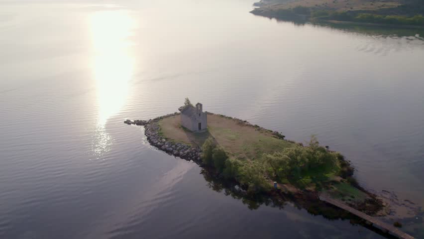 Aerial view of tranquil lake with historic church and serene coastline, Posedarje, Croatia.