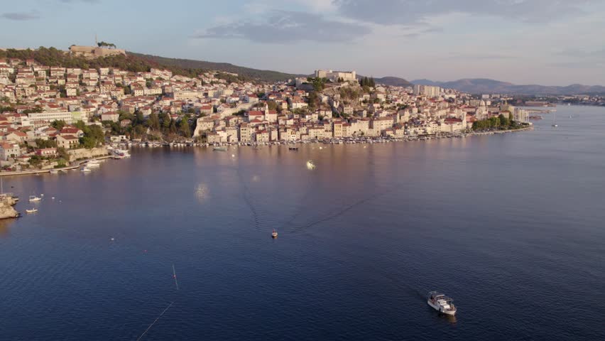 Aerial view of old town, coast, boat, sea, fortress, church in sunset, Sibenik, Croatia.