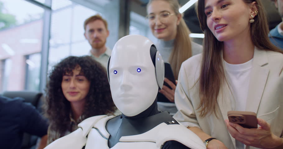 Multi-ethnic group of people surrounding robot. Giving command to press specific key on keyboard in front of gadget. Bionic person complies and performs request correctly. Team happy about success.