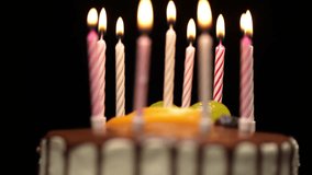 Lit birthday candles flicker on a chocolate-covered cake. The camera gradually zooms in, bringing the shot into focus against a dark, black background. - Powered by Shutterstock - Get 15% off with code: PIKWIZARD15