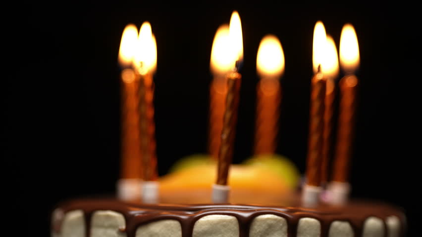 Birthday cake with lit candles, as the camera slowly pulls back to reveal the entire cake.