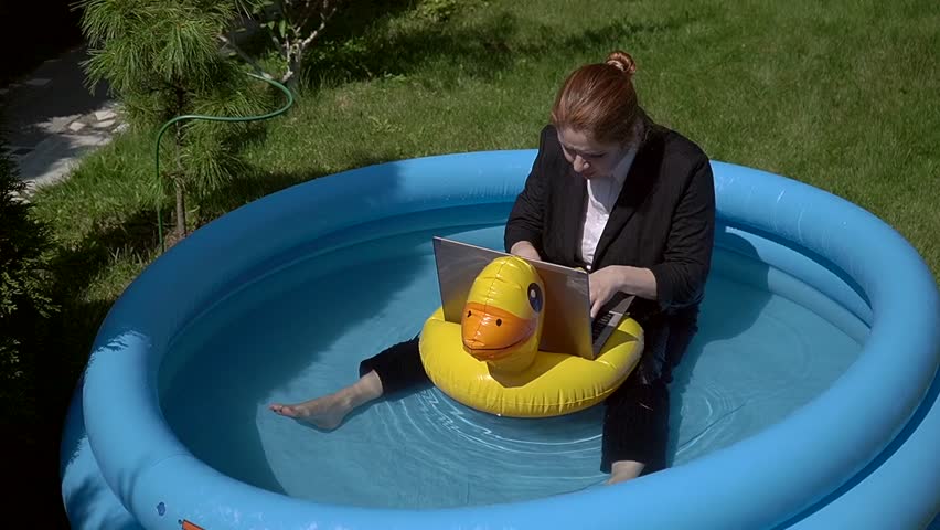 Caucasian business woman working on laptop while sitting in swimming pool. 