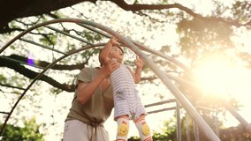 Asian boy plays having fun on the monkey bars at playground, While his mother offering support and ensuring his safety.  active play, and the joy of skill development. - Powered by Shutterstock - Get 15% off with code: PIKWIZARD15