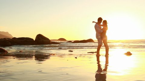 Passionate couple holding each other on the beach at sunset.  Stock Video