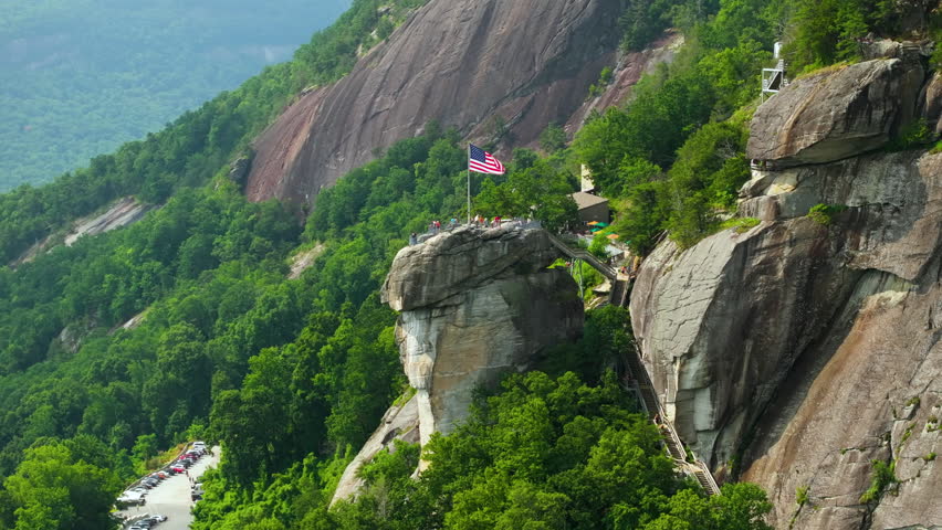 Aerial view of Chimney Rock with flattering American national flag and many tourists at Chimney Rock State Park in North Carolina, USA. Travel destination spot in Appalachian mountains.