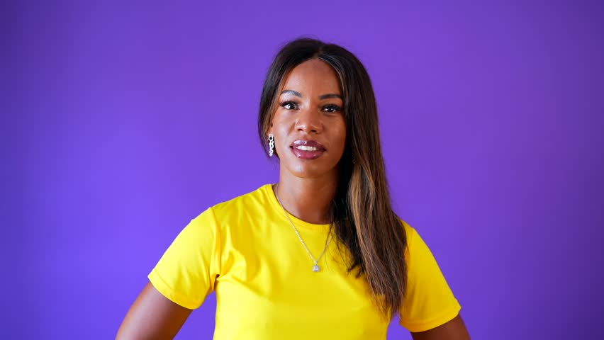 Studio portrait with purple background of a happy african young woman looking up and laughing