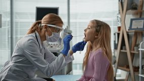 Doctor taking saliva sample in examination room closeup. Child health checkup. Woman nurse in protective mask performing swab test for analysis treatment in hospital. Pediatrician appointment concept - Powered by Shutterstock - Get 15% off with code: PIKWIZARD15