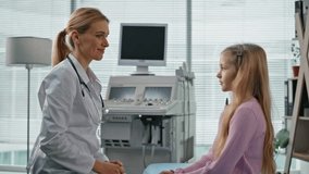 Medical worker consulting kid during appointment. Closeup cheerful young patient giving high five to smiling pediatrician in examination room. Friendly doctor measuring temperature after flu disease - Powered by Shutterstock - Get 15% off with code: PIKWIZARD15