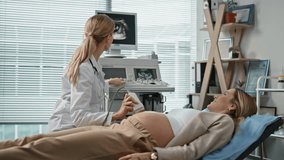 Happy expectant visiting ultrasound procedure in clinic. Smiling doctor showing pregnancy screening on monitor talking future mother in examination room. Woman professional using sonogram machine. - Powered by Shutterstock - Get 15% off with code: PIKWIZARD15