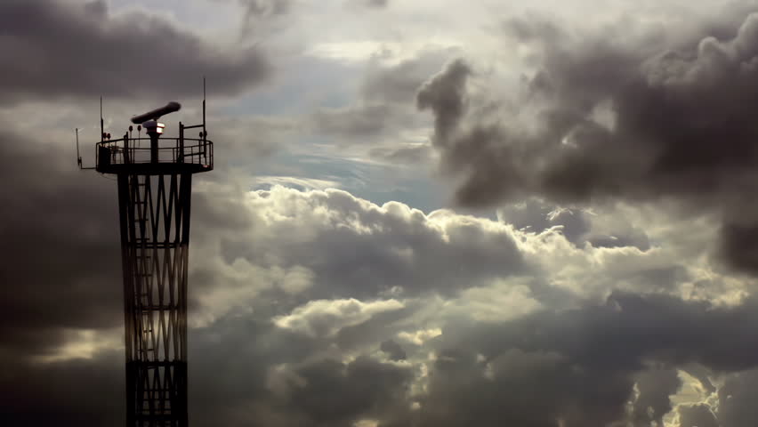 Storm Quickly Approaching to Airport. Communication tower with a rotating antenna and flashing signal lights against the background of rapidly changing weather at dusk