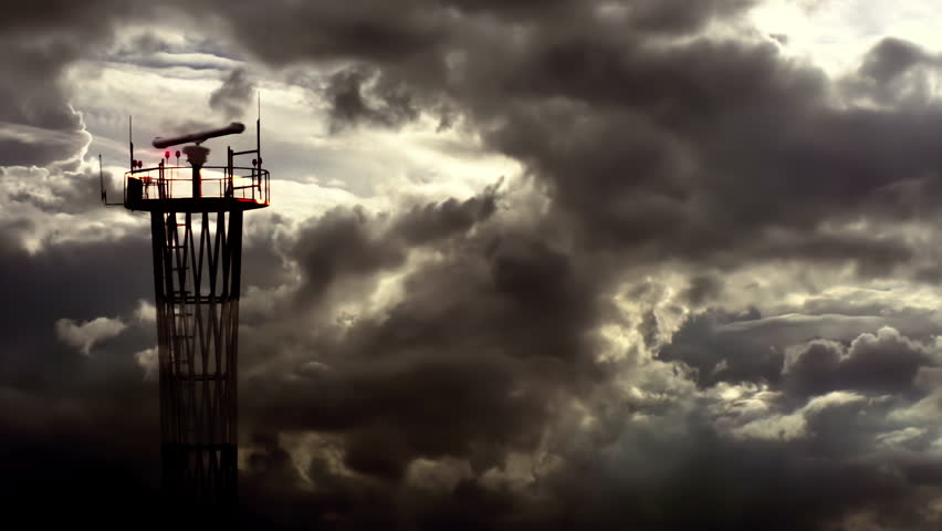 Storm Quickly Approaching to Airport. Communication tower with a rotating antenna and flashing signal lights against the background of rapidly changing weather at dusk