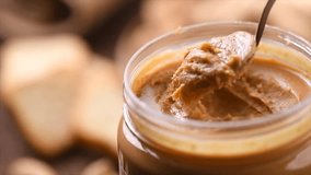 Peanut butter in a glass jar. Creamy smooth peanut butter. Mixing with a spoon, making sandwich, organic food. American cuisine. Slow motion - Powered by Shutterstock - Get 15% off with code: PIKWIZARD15