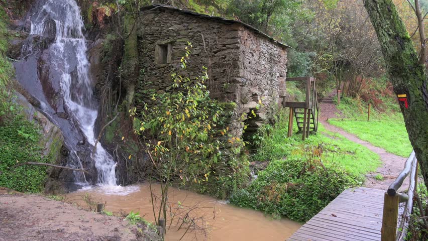 Water mill in the forest, next to a waterfall. Hiking trail.