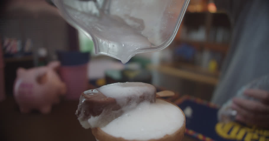 Beautiful slow motion shot pouring cocktail over a glass with a Mexican margarita and a chocolate ice cream on top in a Mexican restaurant.