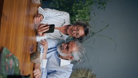 vertical video elderly people sitting at a table together watching social networks on the phone funny videos happy old age elderly couple pleasant memories leisure time in old age warm feelings - Powered by Shutterstock - Get 15% off with code: PIKWIZARD15