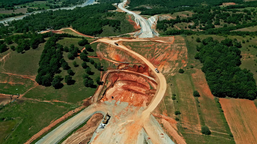 Open quarry with orange colors and working heavy machinery, aerial view