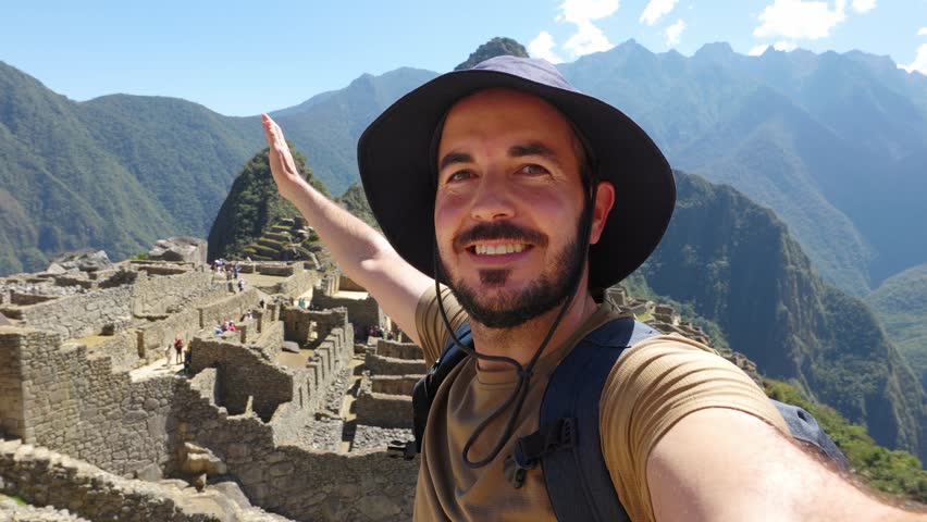 POV video selfie of happy young adult man enjoying Machu Picchu landscape. Joyful traveler enjoying vacation visiting Peru. South american travel holidays concept.