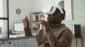 Side chest up shot of young African American male company manager working on project in modern augmented reality headset, gesturing hands during office meeting - Powered by Shutterstock - Get 15% off with code: PIKWIZARD15