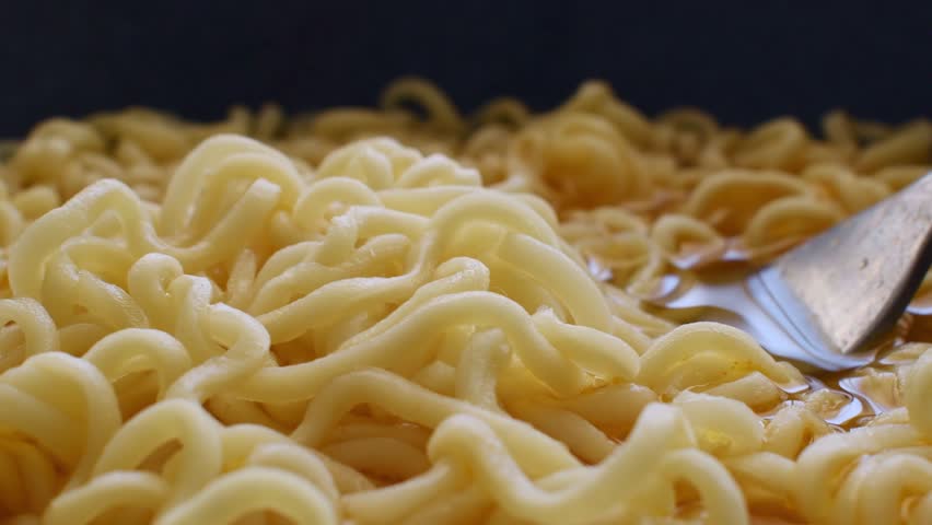 Instant noodle soup close up with a fork. Stirring noodles. Simple and speed food. 