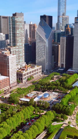 Artistic commemoration of the famous shiny bean sculpture in the center of a Chicago park. Aerial view of the city with trees and skyscrapers. Vertical video.