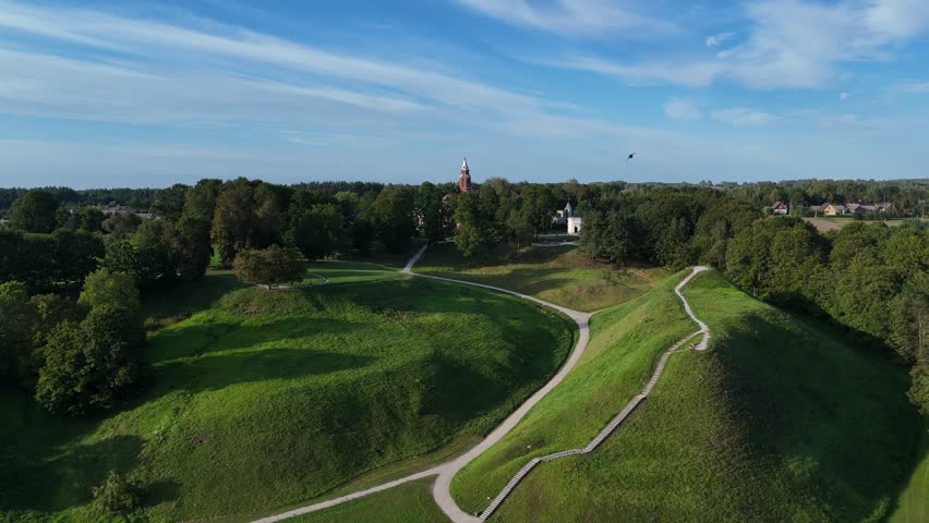 Aerial view of Kernave mounds, historical site in Lithuania. Aerial view of the Kernave mounds, an ancient archaeological site in Lithuania, surrounded by green hills and nature.