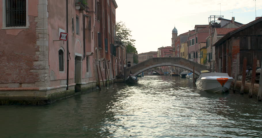 Exploring the serene canals of Venice at dusk with quaint bridges and charming boats