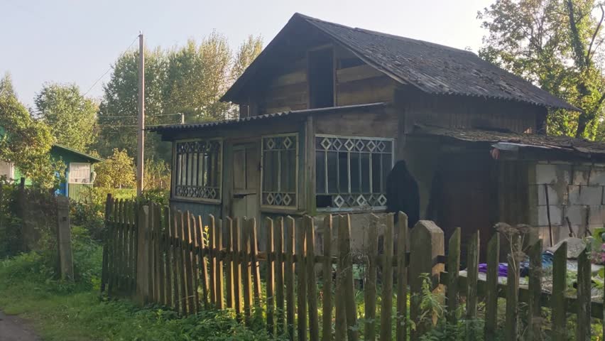 Old wooden abandoned house in the village with a fence 