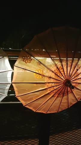 displays several umbrellas lined up at night with lighting behind them