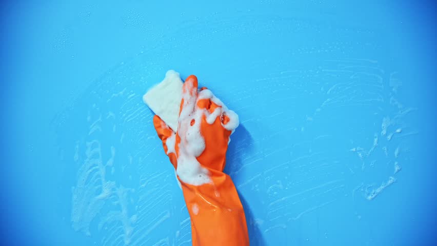 Hand holding sponge for cleaning on blue background