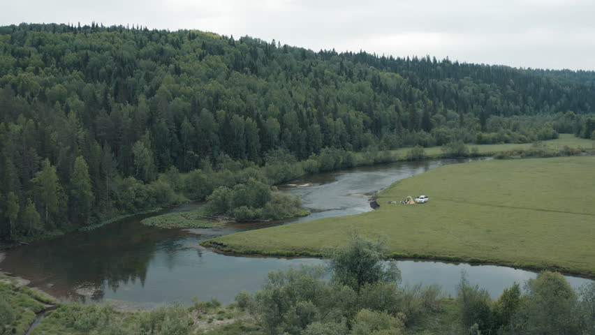 Car trip and camping in the wild. Morning view of the campsite with car and tents set on the river coast in mountains