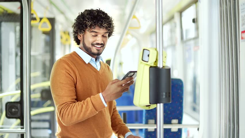 Man using smartphone for fare payment on public transport, standing in modern tram Male paying public city or bus with mobile phone app. validating ticket ride inside trolleybus use application - Powered by Shutterstock - Get 15% off with code: PIKWIZARD15