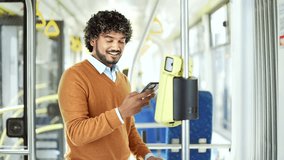 Man using smartphone for fare payment on public transport, standing in modern tram Male paying public city or bus with mobile phone app. validating ticket ride inside trolleybus use application - Powered by Shutterstock - Get 15% off with code: PIKWIZARD15