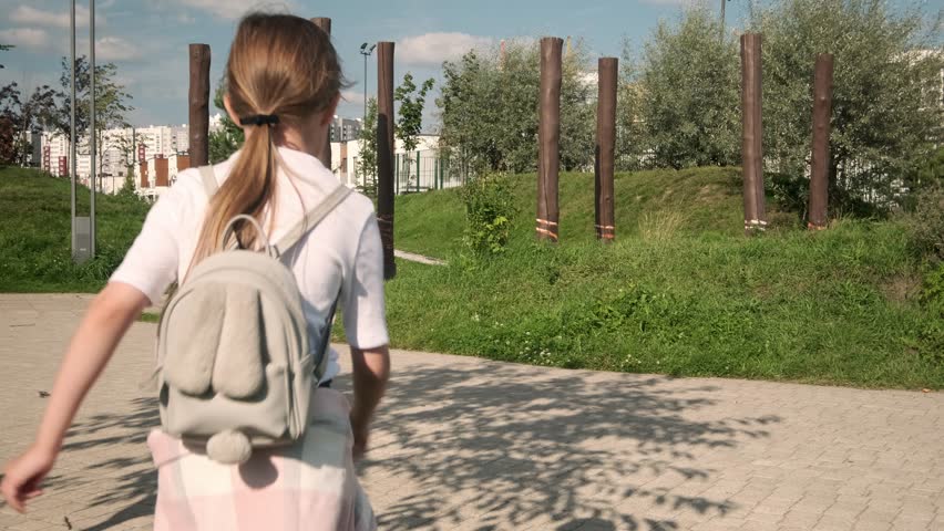 Little girl walks in summer park. Child walks. Child, little girl with backpack goes home from school, plays on street. Child dreams. Family, cheerful childhood