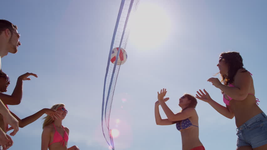 Young multi ethnic people enjoying time together playing beach volleyball weekend break travel tourism
