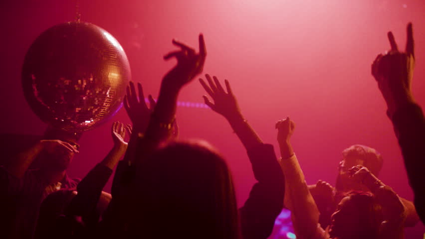 Footage of a crowd during colorful party in different clothes having fun and dancing at a midnight party. Shot in slow-motion