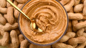 Peanut butter in a glass jar. Creamy smooth peanut butter. Mixing with a spoon, making sandwich, organic food. American cuisine. Top view.  - Powered by Shutterstock - Get 15% off with code: PIKWIZARD15