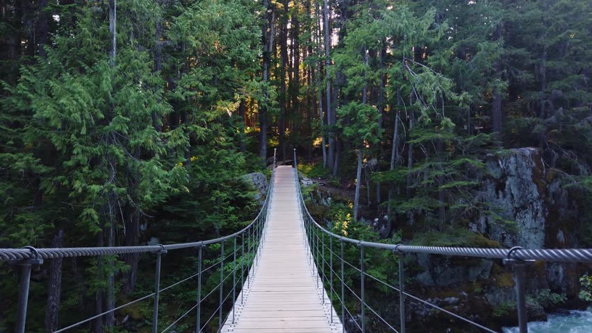 Incredible hiking trail in Whistler, along a suspension bridge over rushing water the Cheakamus River to the past train ruins abandoned in a forest. Whistler, British Columbia, Canada.