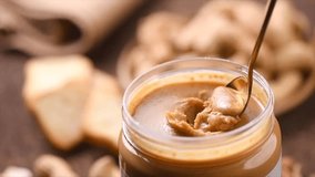 Peanut butter in a glass jar. Creamy smooth peanut butter. Mixing with a spoon, making sandwich, organic food. American cuisine. Slow motion.  - Powered by Shutterstock - Get 15% off with code: PIKWIZARD15