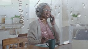 Animation of rain falling over senior african american woman using smartphone at home. Global connections, computing and data processing concept digitally generated video. - Powered by Shutterstock - Get 15% off with code: PIKWIZARD15