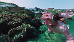 Girl child swims and snorkels under water. Kid dives into the ocean wearing goggles and looks at the underwater world. High quality 4k footage - Powered by Shutterstock - Get 15% off with code: PIKWIZARD15