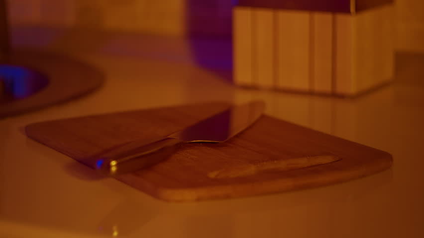 Kitchen utencils on wooden board with chef knife on it. Knife on cutting board shot on kitchen counter isolated.