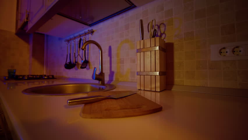 Home cooking of small bamboo cutting board and chef knife on the counter top. Kitchen utencils on display near the sink.