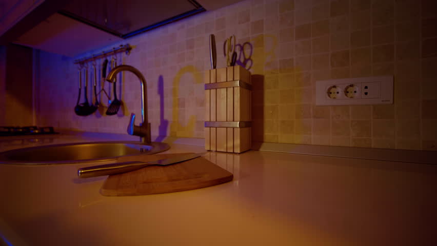 Small bamboo cutting board and chef knife on the counter top. Kitchen utencils on display near the sink.