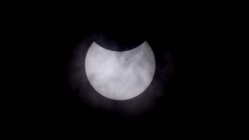 A breathtaking moment is captured through a solar filter as a plane crosses the path of the partially eclipsed sun. The filter dims the intense brightness, allowing the silhouette to stand out.