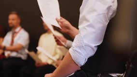 Choir rehearsal, vocal class singing in the auditorium hall, group of students on stage holding white sheets and singing, orchestra vocals class in music school with a teacher, adults sing in chorus - Powered by Shutterstock - Get 15% off with code: PIKWIZARD15