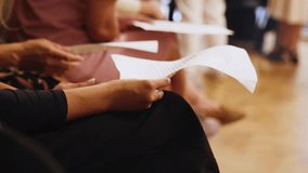 Choir rehearsal, vocal class singing in the auditorium hall, group of students on stage holding white sheets and singing, orchestra vocals class in music school with a teacher, adults sing in chorus - Powered by Shutterstock - Get 15% off with code: PIKWIZARD15