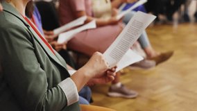 Choir rehearsal, vocal class singing in the auditorium hall, group of students on stage holding white sheets and singing, orchestra vocals class in music school with a teacher, adults sing in chorus - Powered by Shutterstock - Get 15% off with code: PIKWIZARD15