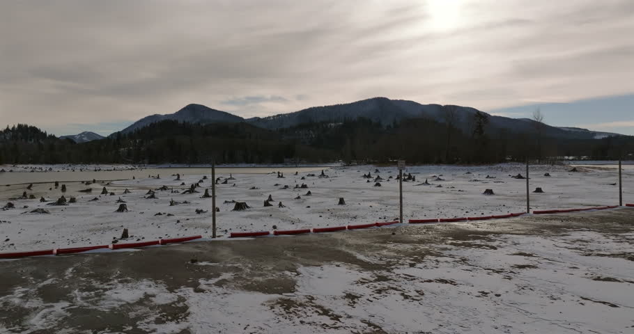 Snow-covered landscape with tree stumps and distant mountains under overcast sky, Washington State, USA