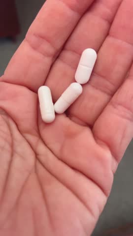 White tablets and capsules in hand. Concept of medicines, medicines and vitamins for humans. Treatment and prevention of diseases. Production of medicines, vitamins and biologically active substances.